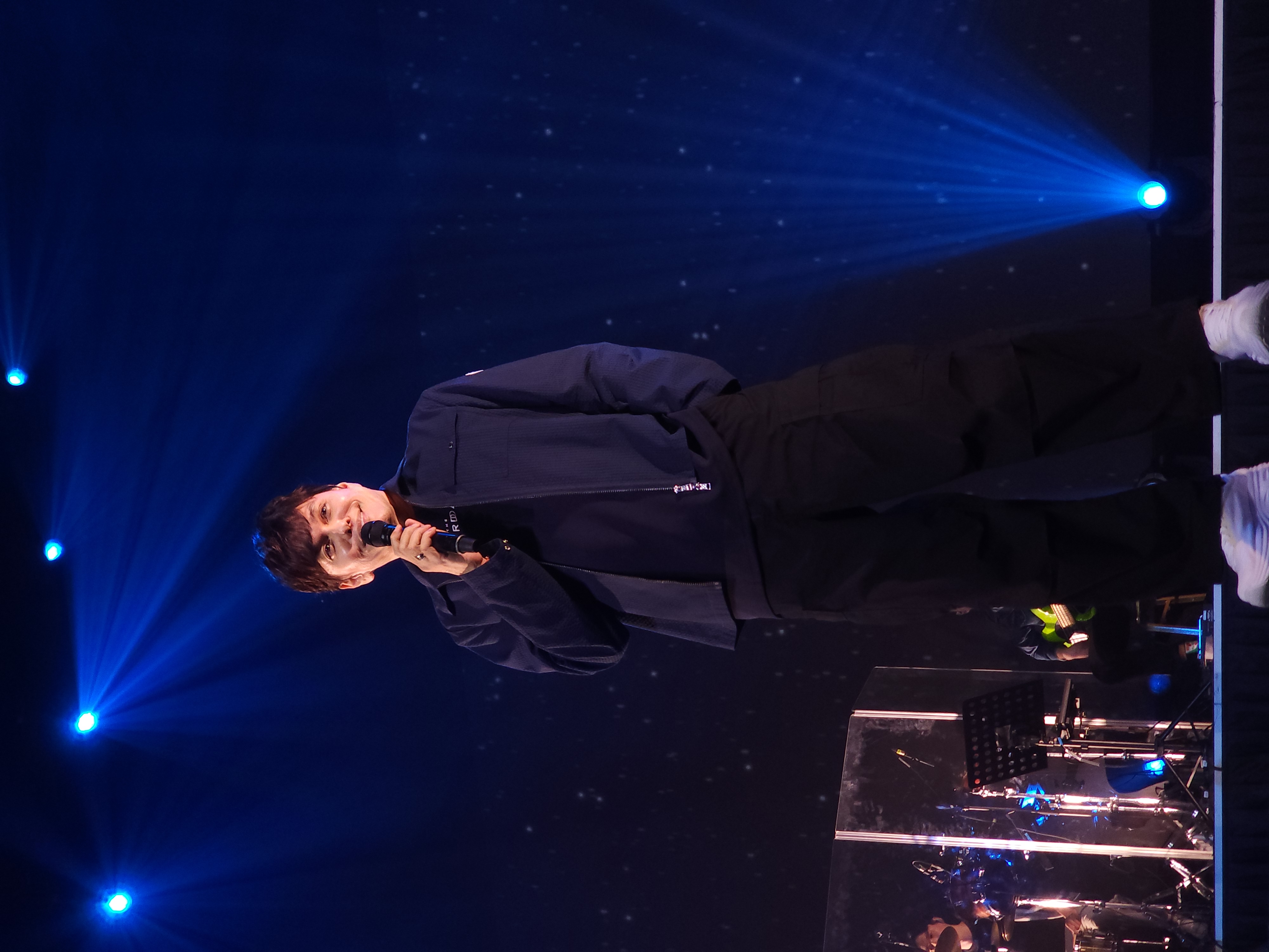 A singer performing beneath blue stage lights