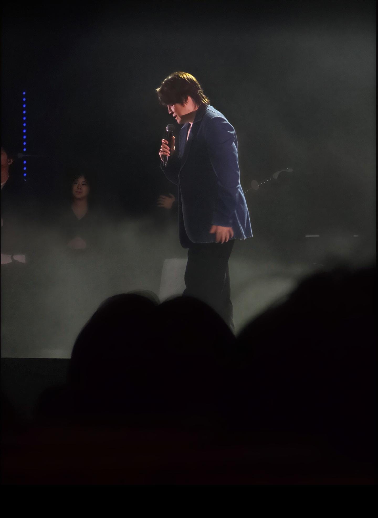 A singer standing in a spotlight during a concert