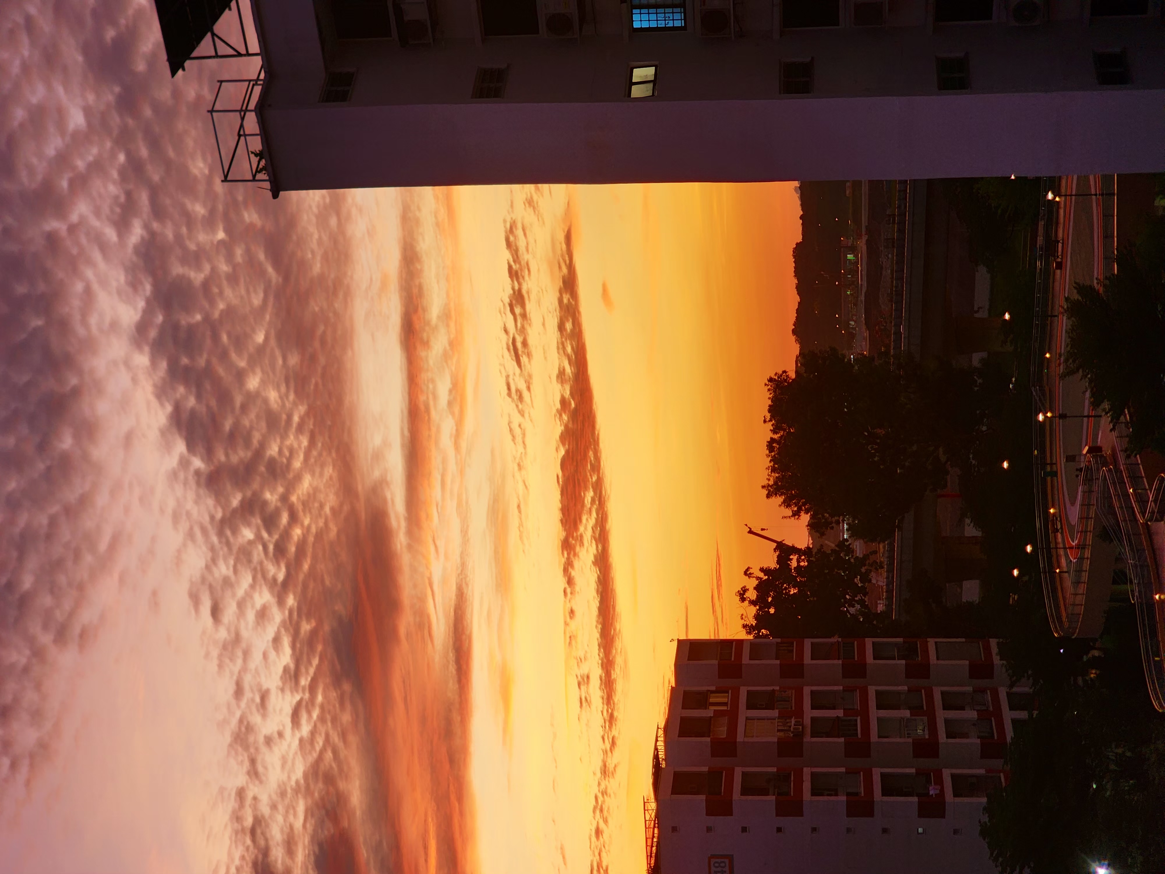 A vivid sunset breaking through clouds above apartment blocks